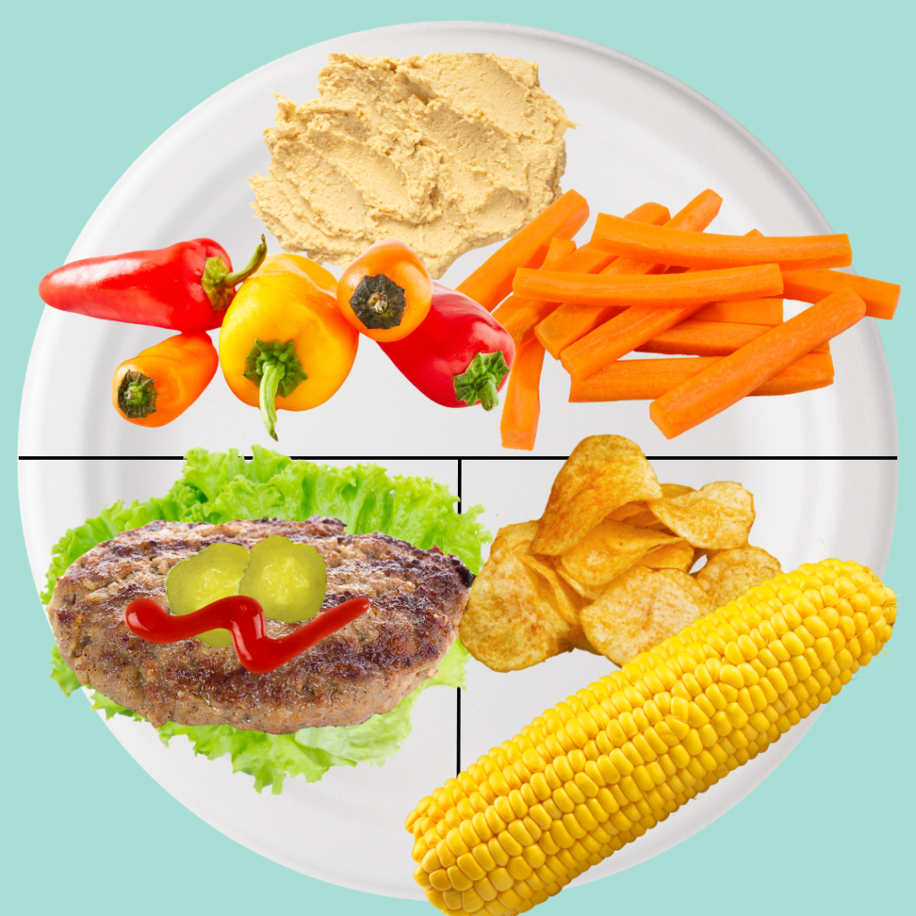 Balanced plate for diabetes-friendly cookout meal with veggies and hummus, chips, corn and a burger wrapped in lettuce with pickles and ketchup.